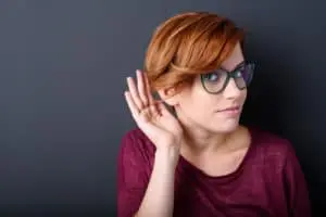 woman with a hearing her hand behind ear 300x200
